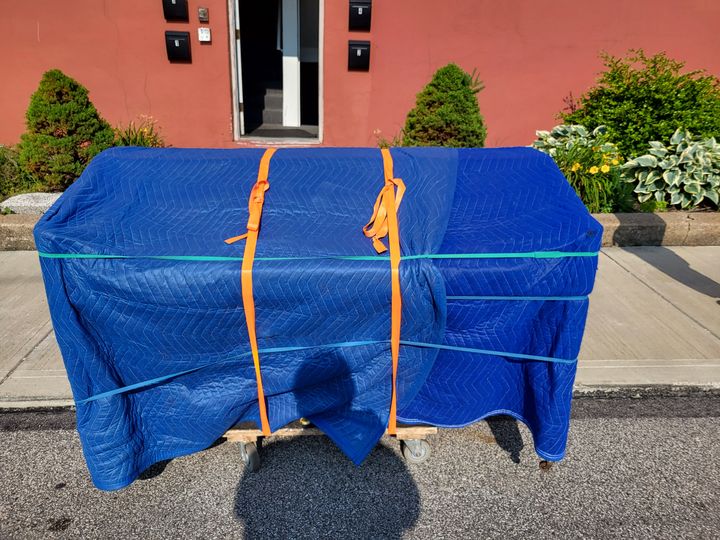 Piano wrapped in blue moving blankets outdoors (Piano Moving Services) by Moving Pros CLE